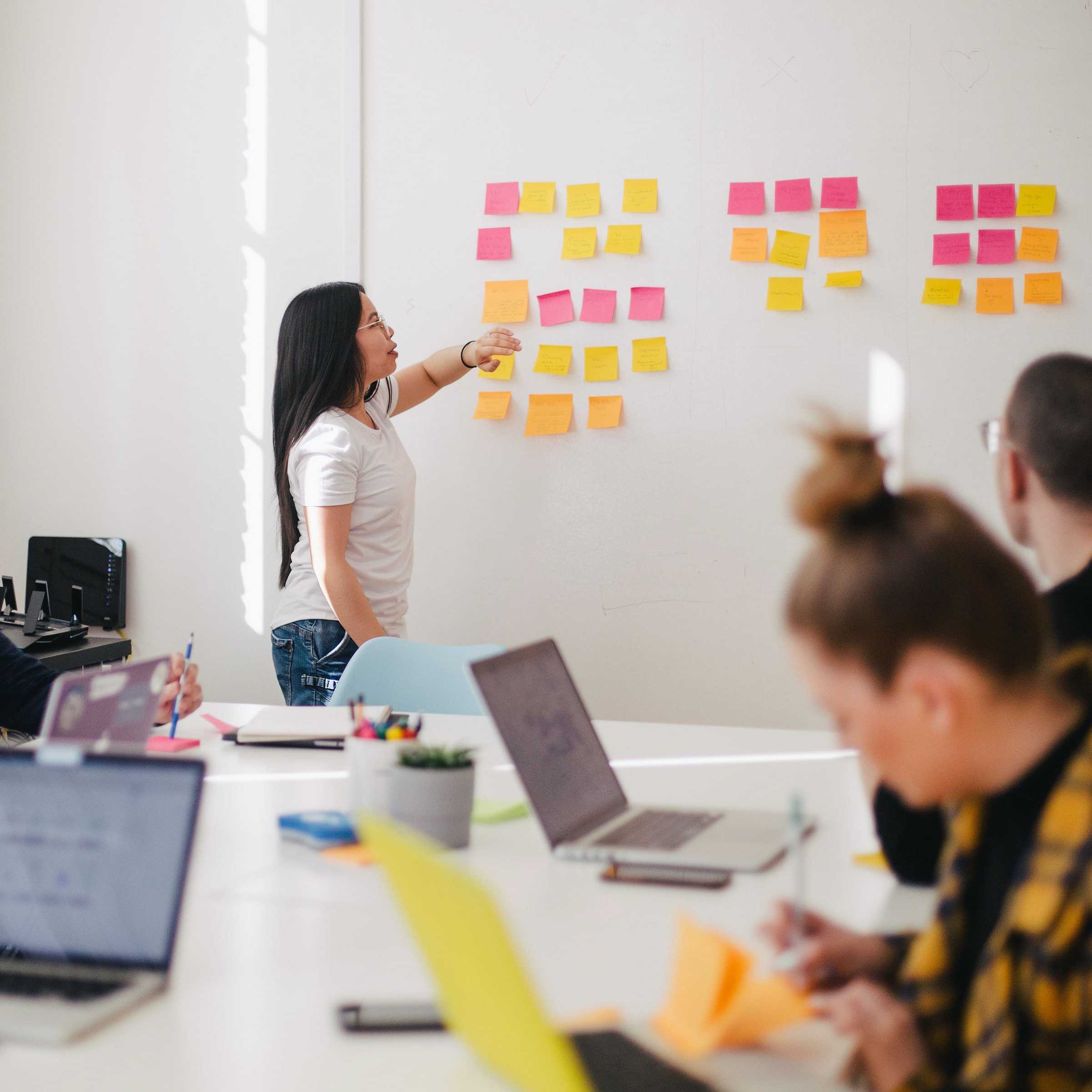 accompagnement diversité et inclusion : une femme devant un tableau blanc et des post-it dans une salle de conférence